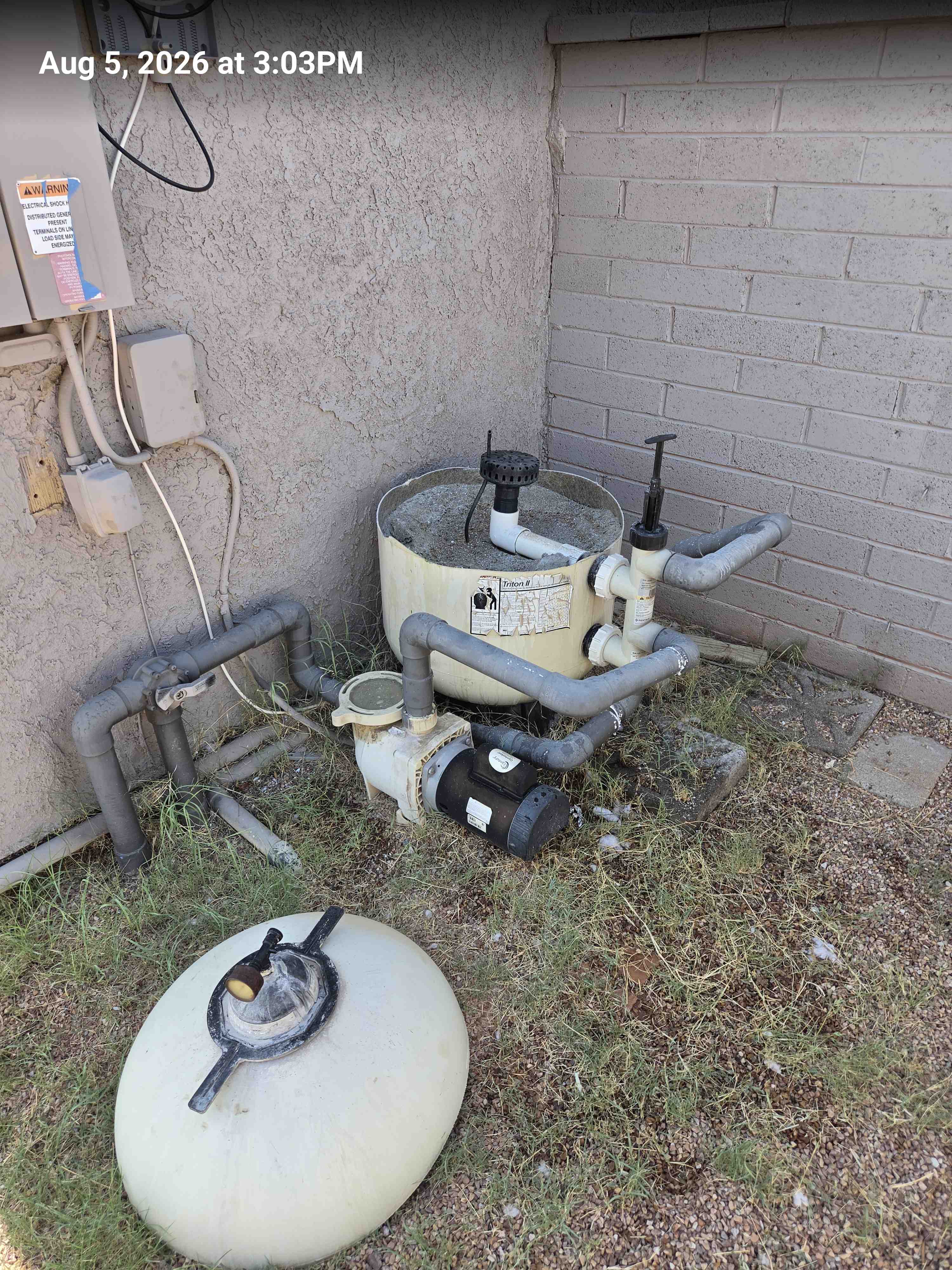 Sand filter with the lid off on the gravel, old pump still in place, stamped Aug 5, 2026 at 3:03 PM.