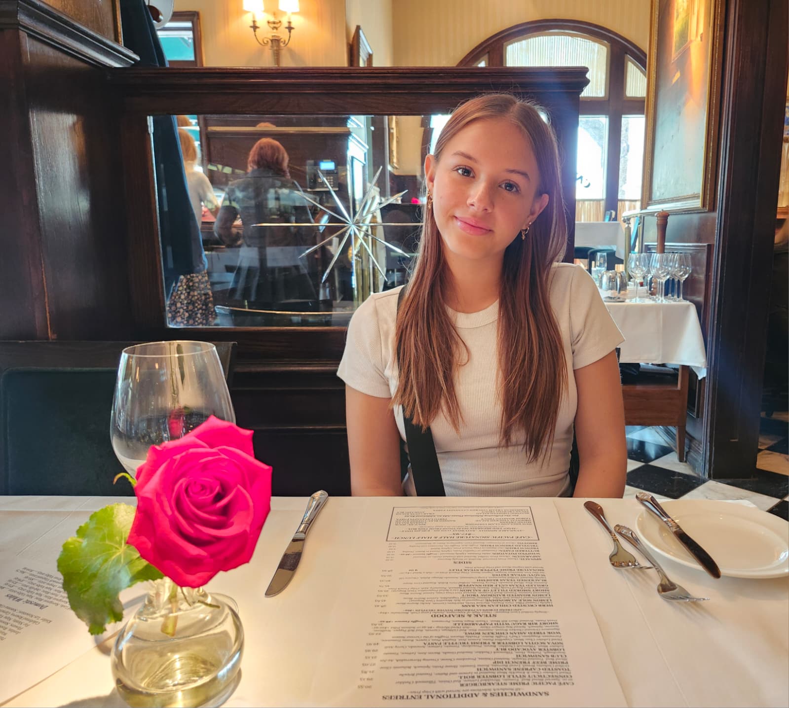 Taylor Rose Knowlton at dinner — the vivid pink rose beside her mirrors the Taylor's House colors perfectly
