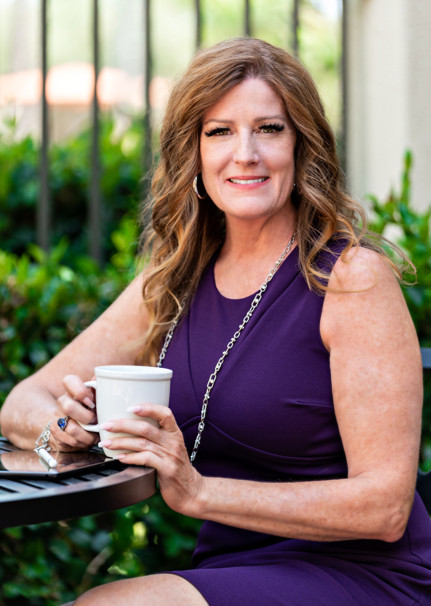 Marcia Riner, business growth strategist in a purple dress drinking coffee