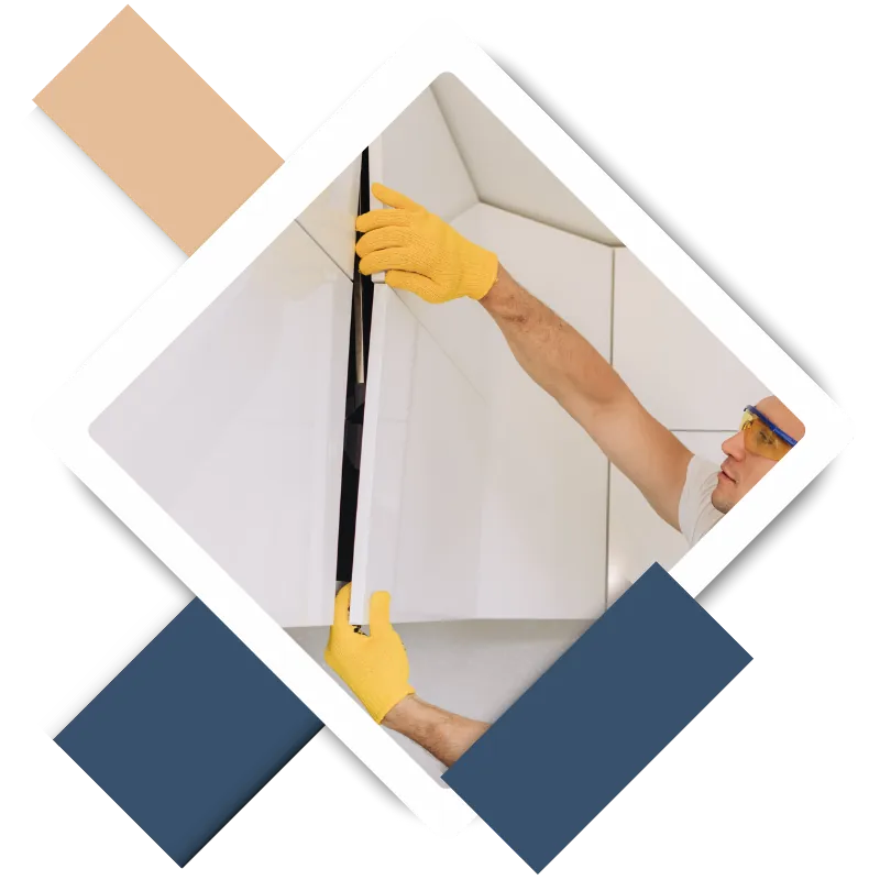 Man wearing yellow gloves and safety glasses measuring a wall during home repair, illustrating professional handyman services in Kingwood, TX.
