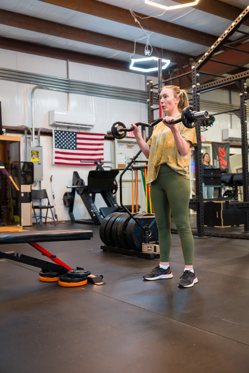 A woman lifts a curl bar at Yellow Brick Fitness in White House, TN