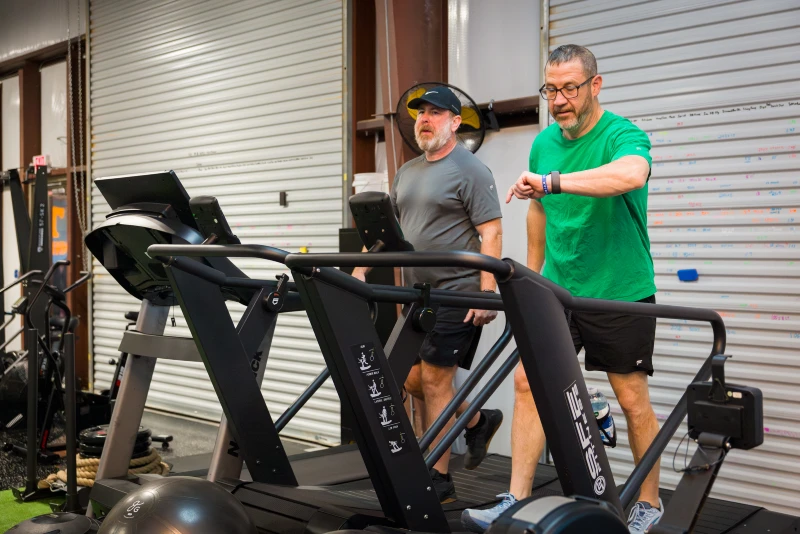 Two men walk on treadmills together at Yellow Brick Fitness in White House, TN