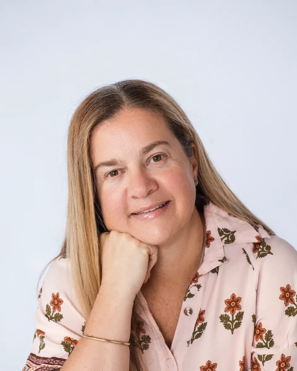Tammy smiling, chin resting on her hand, in a floral shirt