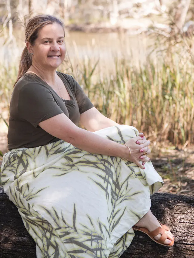 Tammy sitting on a log by the lagoon