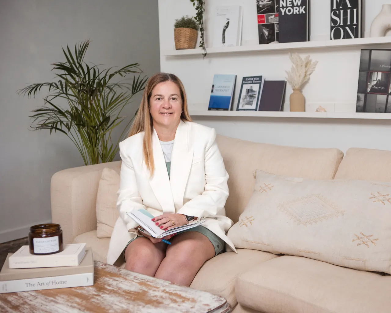 Tammy seated on a linen sofa in a calm, light-filled therapy room