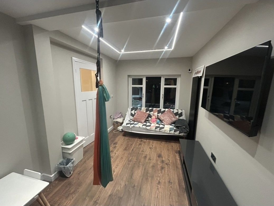 Long converted family room with an aerial silk swing, wall-mounted TV and LED ceiling channel