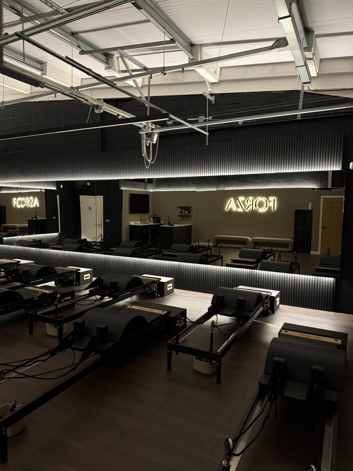 Forza studio fit-out with reformer machines, black acoustic slat walls and LED lighting