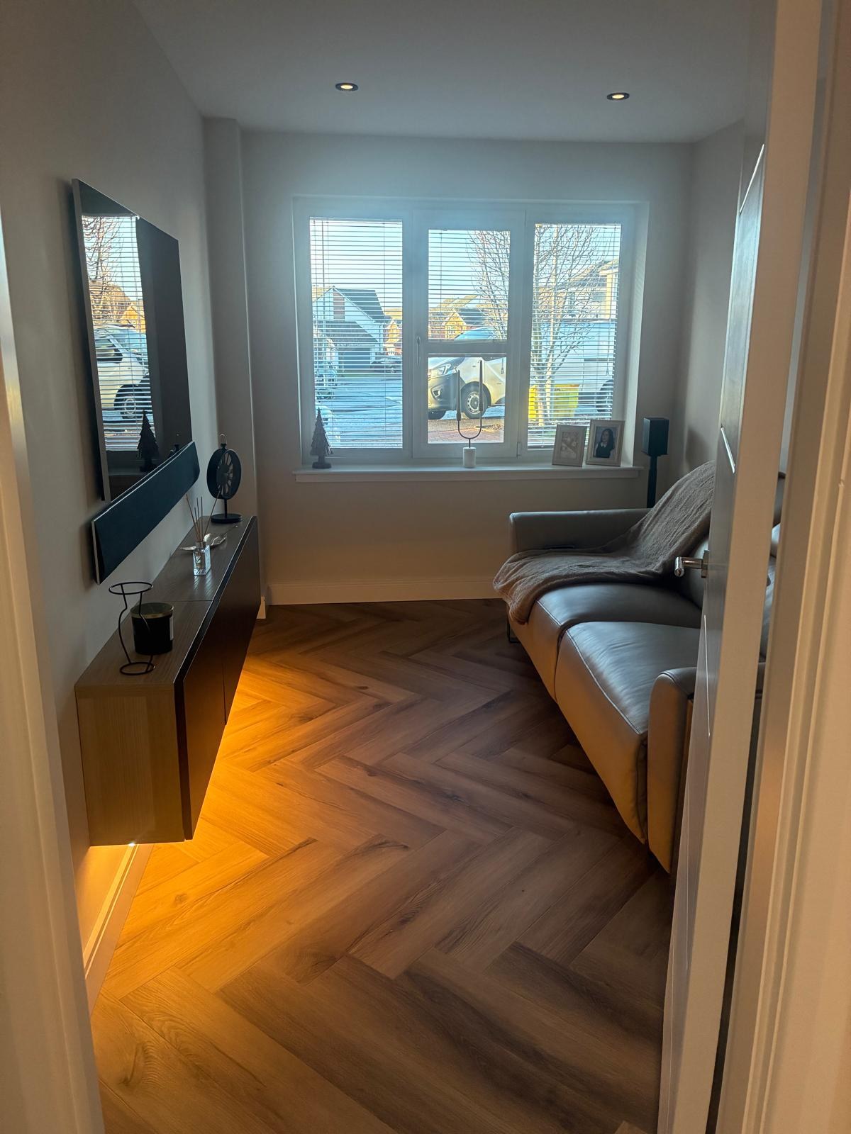 Converted garage lounge with herringbone floor, wall-mounted TV and floating unit with LED underglow