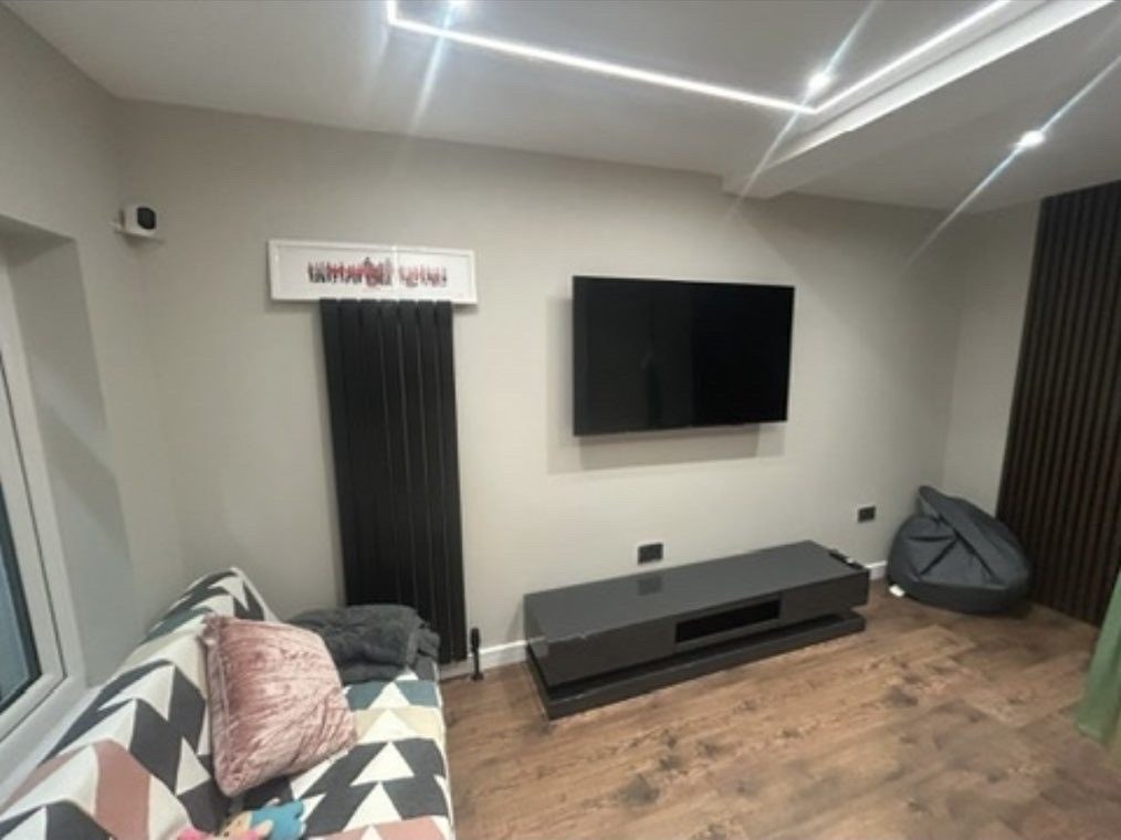 Garage converted into a media room by M4 Contractors, with LED ceiling channel and designer radiator
