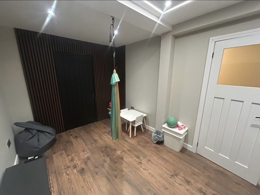 Converted playroom with a dark timber slat feature wall and children's table and chairs
