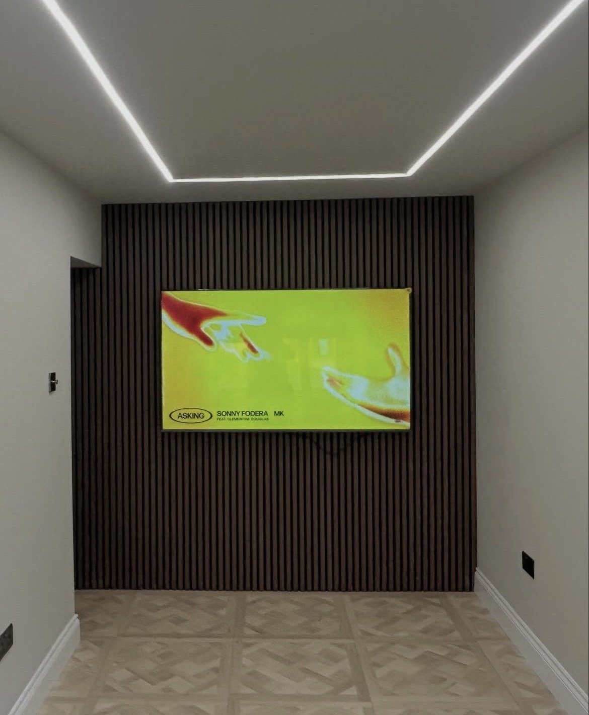 Full-height dark timber slat wall with mounted TV and LED channel lighting around the ceiling