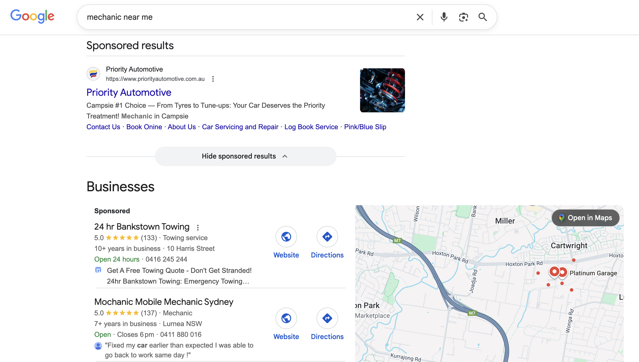 A close-up of a laptop on a workbench displaying a Google Ads dashboard, with mechanic tools and a coffee cup nearby. The workspace is tidy, the lighting is natural, and the scene feels approachable and professional, emphasizing digital marketing for auto shops.