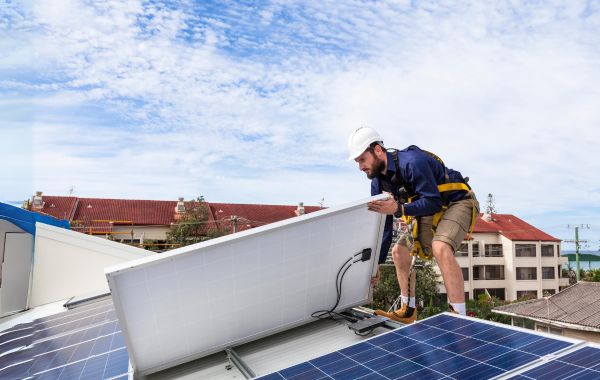Installer lifting a solar panel onto a roof