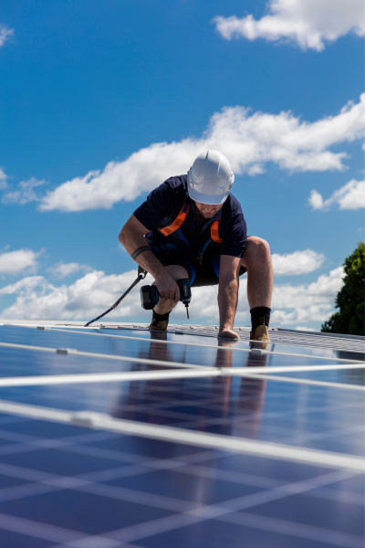 Installer fastening a solar panel on a roof
