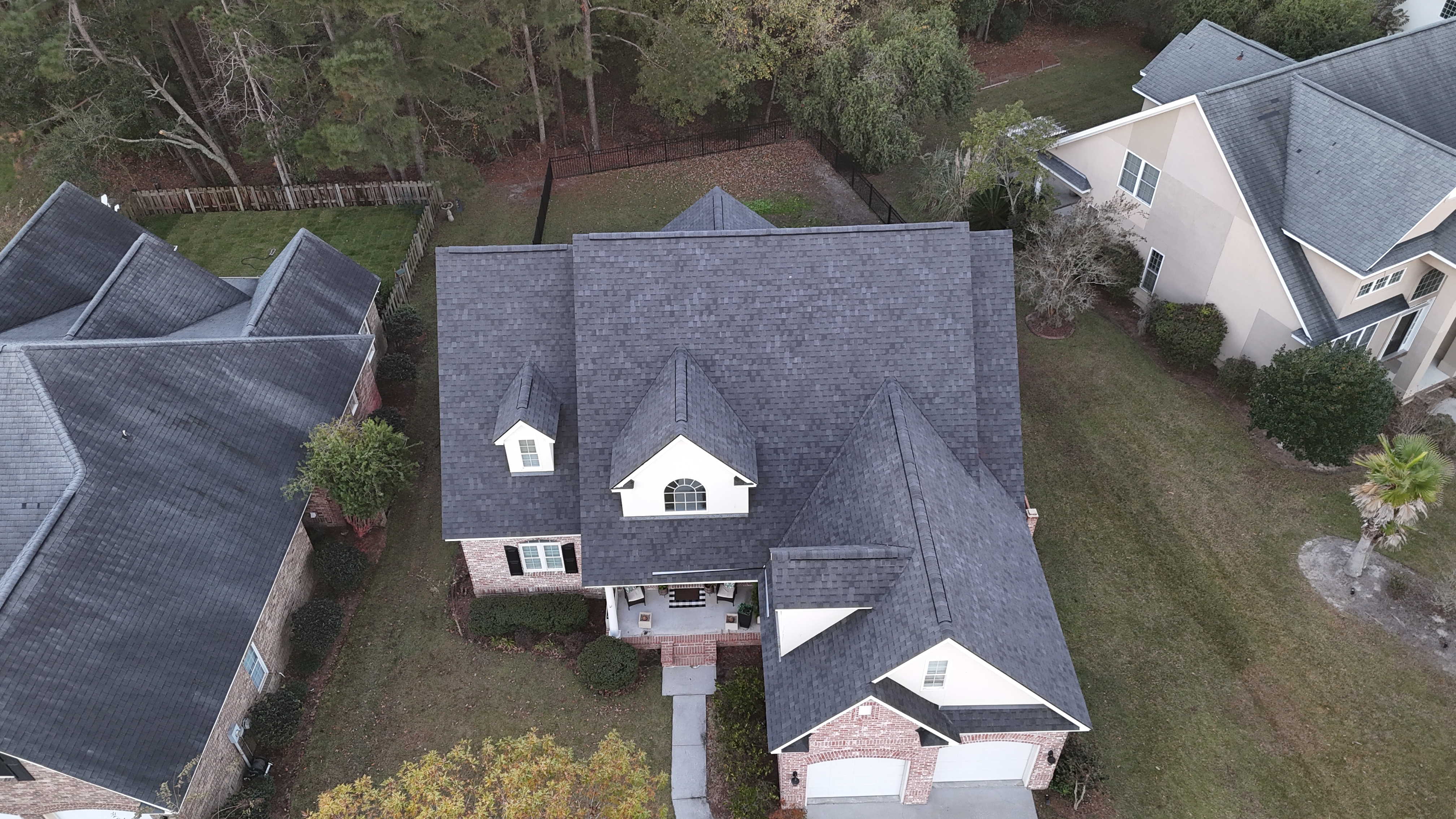 Aerial view of a residential property featuring a newly installed dark shingle roof, showcasing Precision Roofing USA's craftsmanship and quality in roofing solutions.