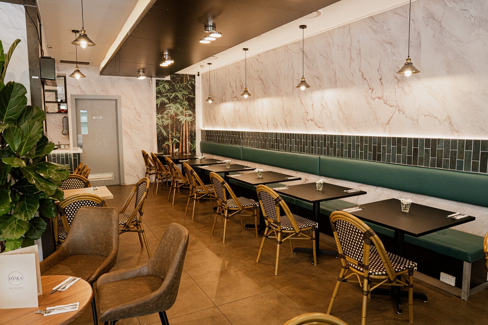The dining room at Danka Café & Lounge — banquette seating, rattan chairs and pendant lights