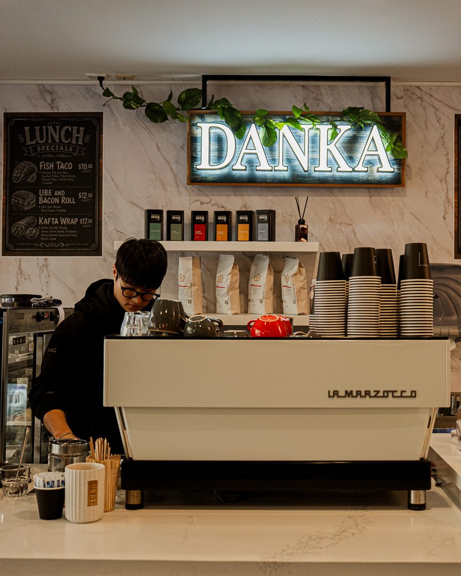A Danka barista at the La Marzocco espresso machine beneath the glowing DANKA neon sign