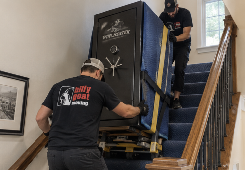 Professional gun safe movers carefully moving a heavy safe on stairs in a Fort Collins home