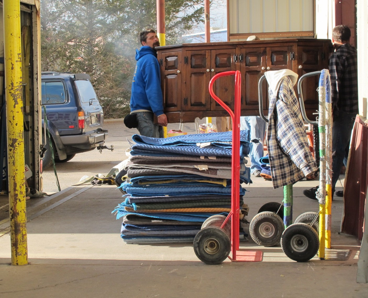 Local Fort Collins moving team carrying furniture out of a home on a sunny moving day