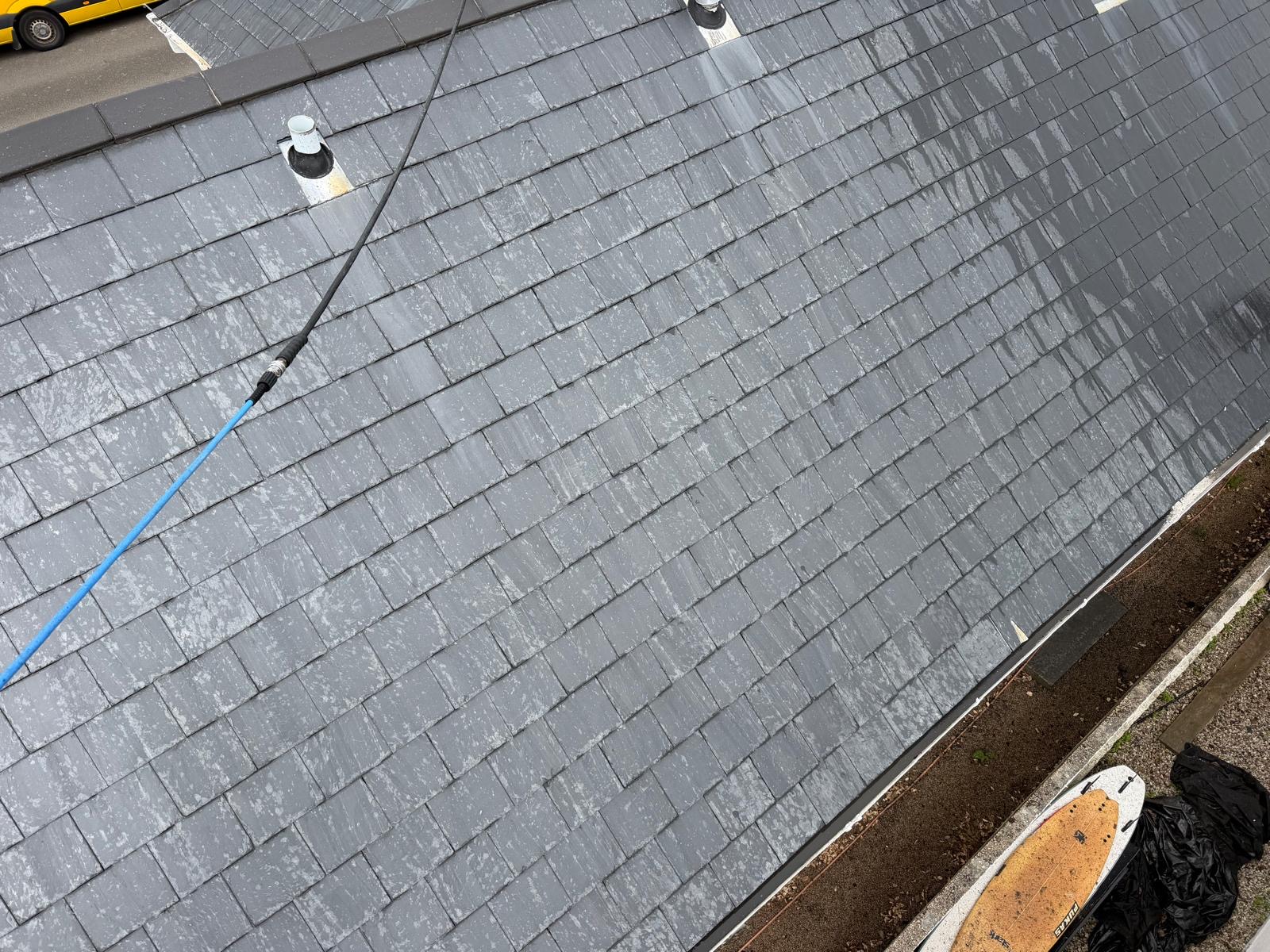 Roof cleaning work in progress on a grey slate-type roof.