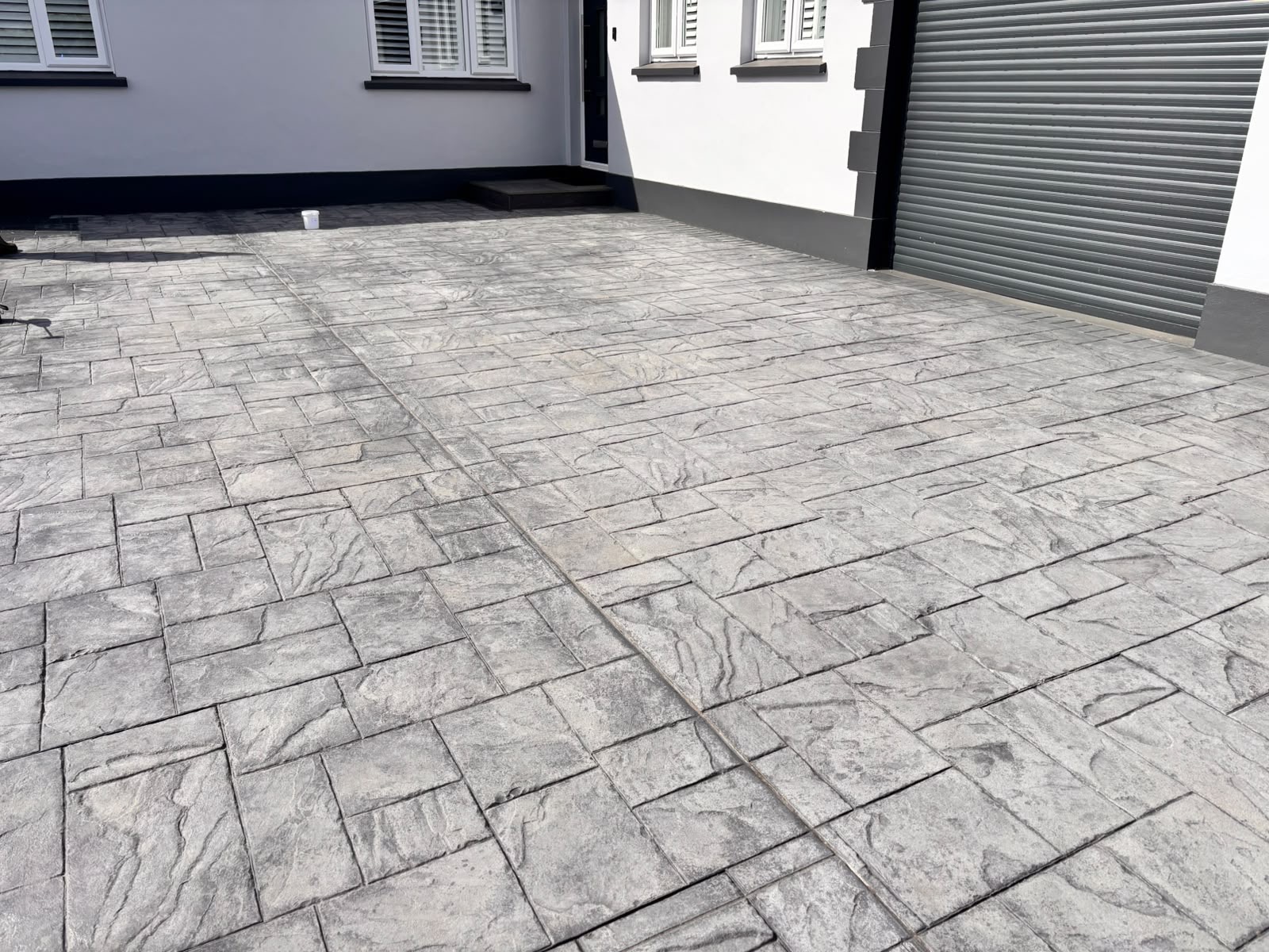 Faded imprinted concrete driveway before restoration.