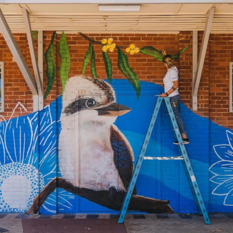Painting a kookaburra mural on a ladder