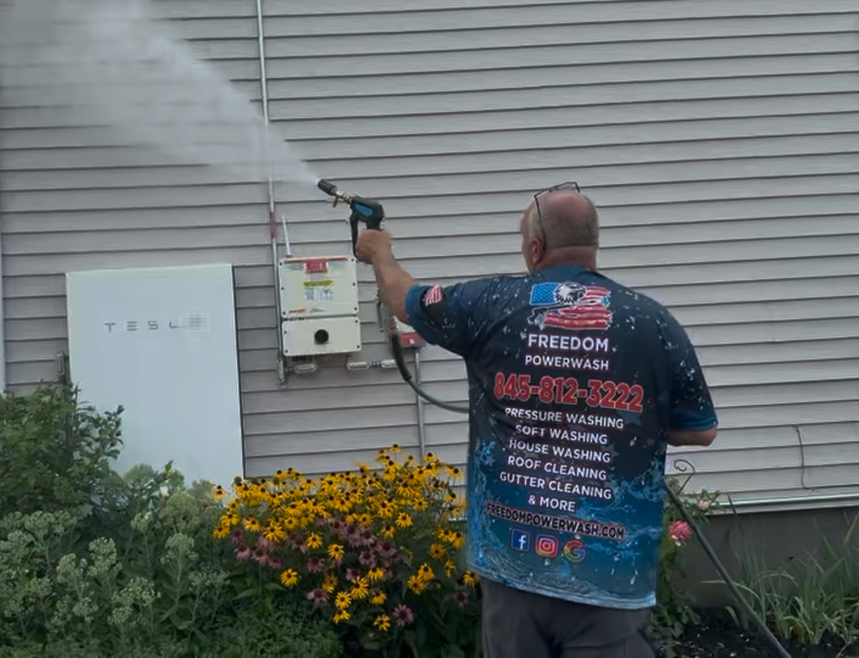 Professional house washing technician cleaning vinyl siding with low-pressure soft washing methods in the Hudson Valley.