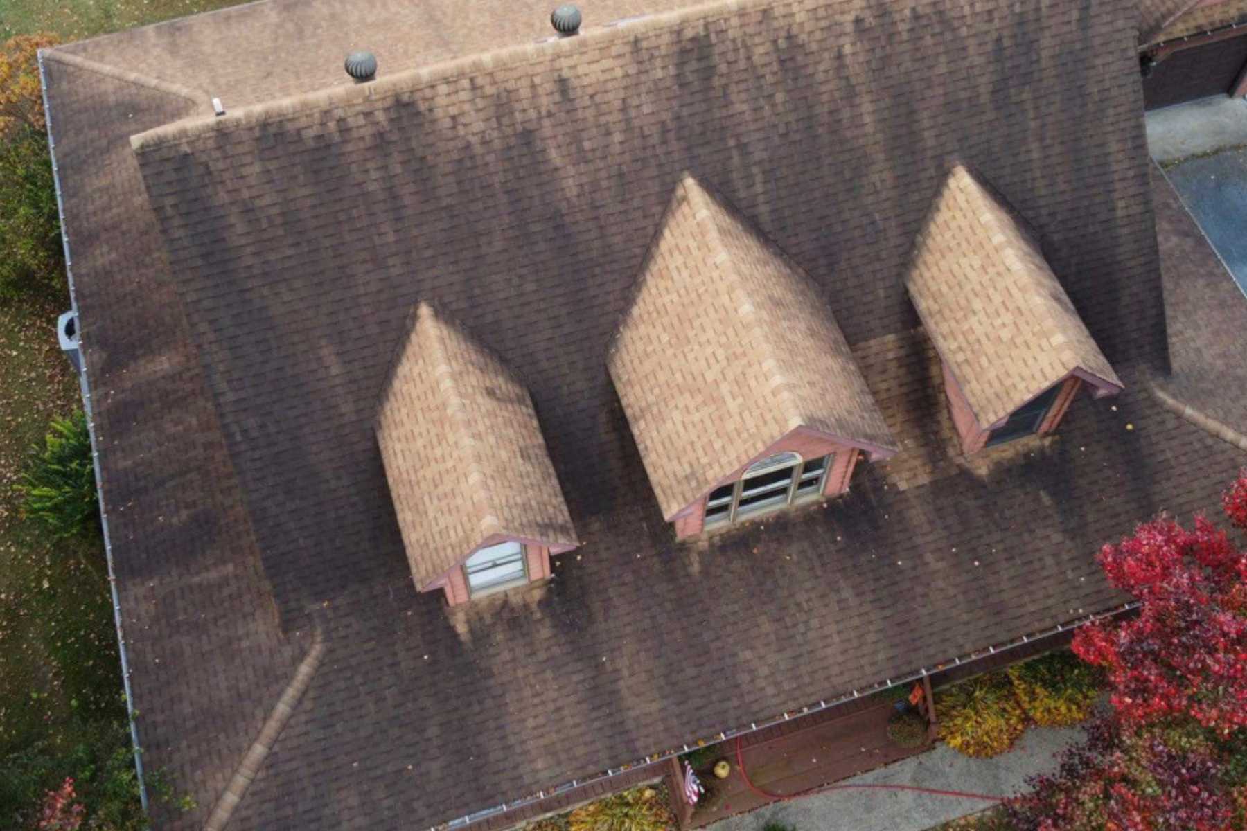 Aerial view of a shingle roof with heavy black algae streaks and organic staining before professional roof soft washing in Milan, NY.
