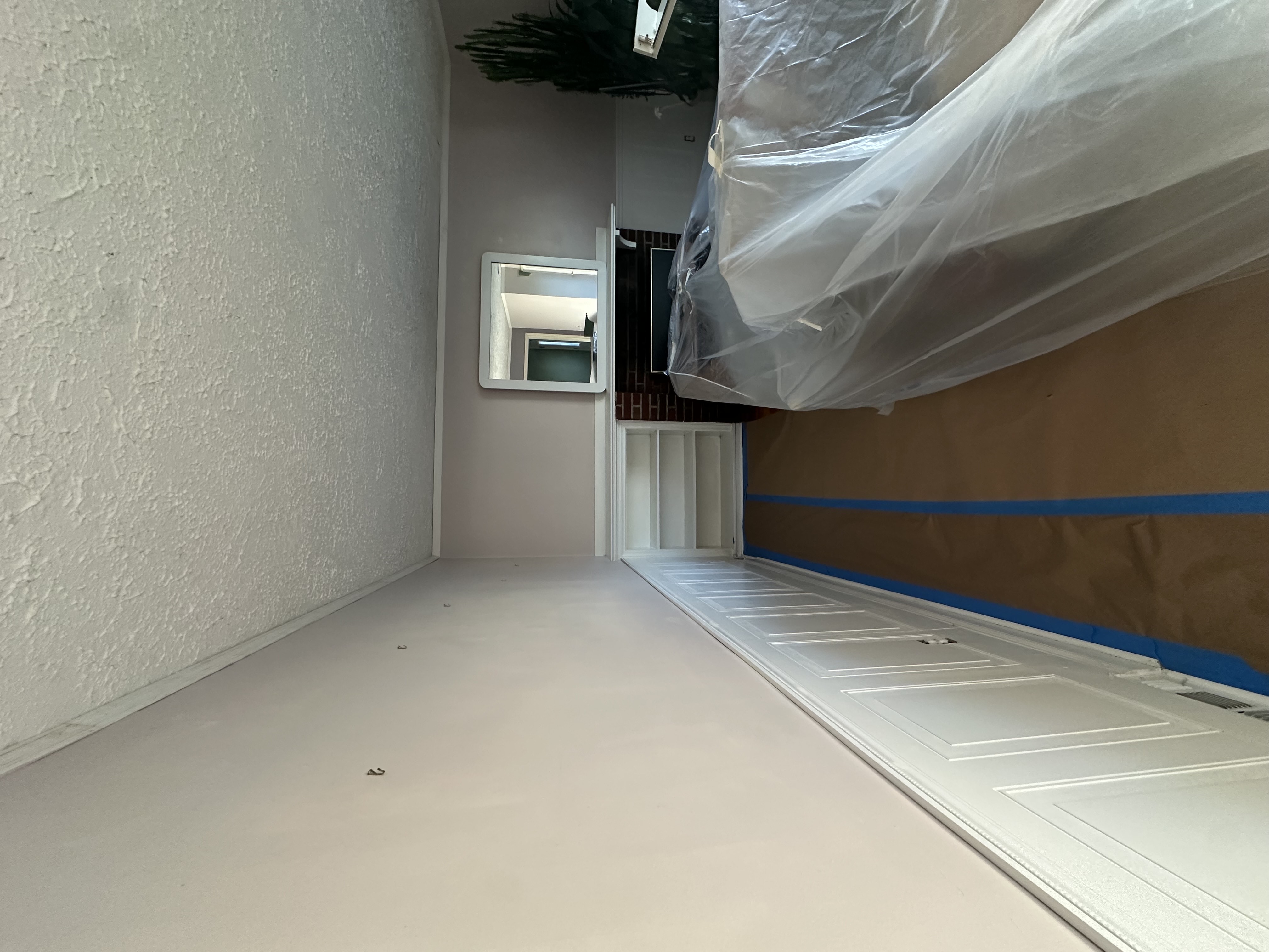 Living room with furniture wrapped in plastic and floors covered before painting