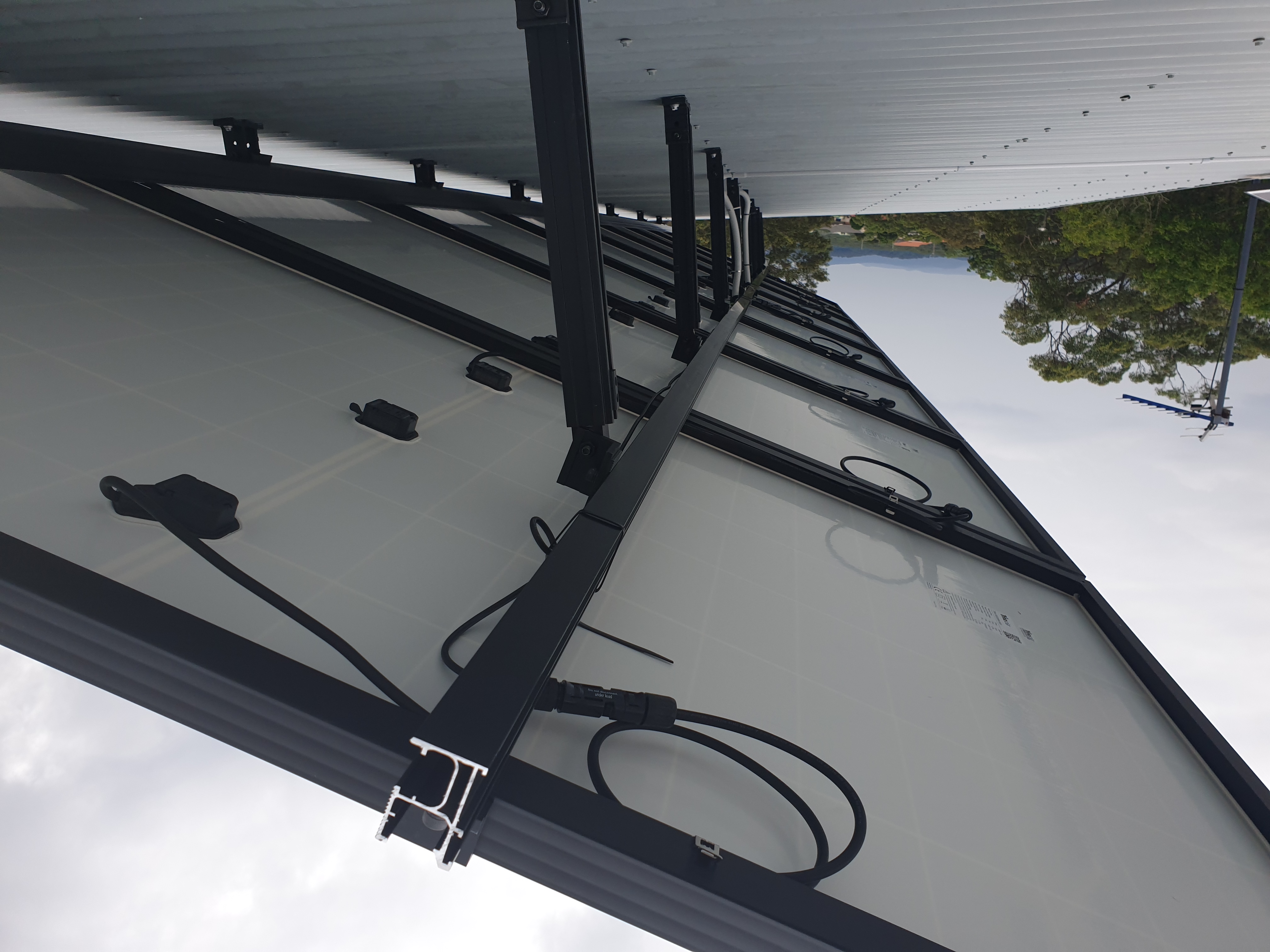 Underside detail of a rooftop array showing mounting rails, brackets, and cable routing.