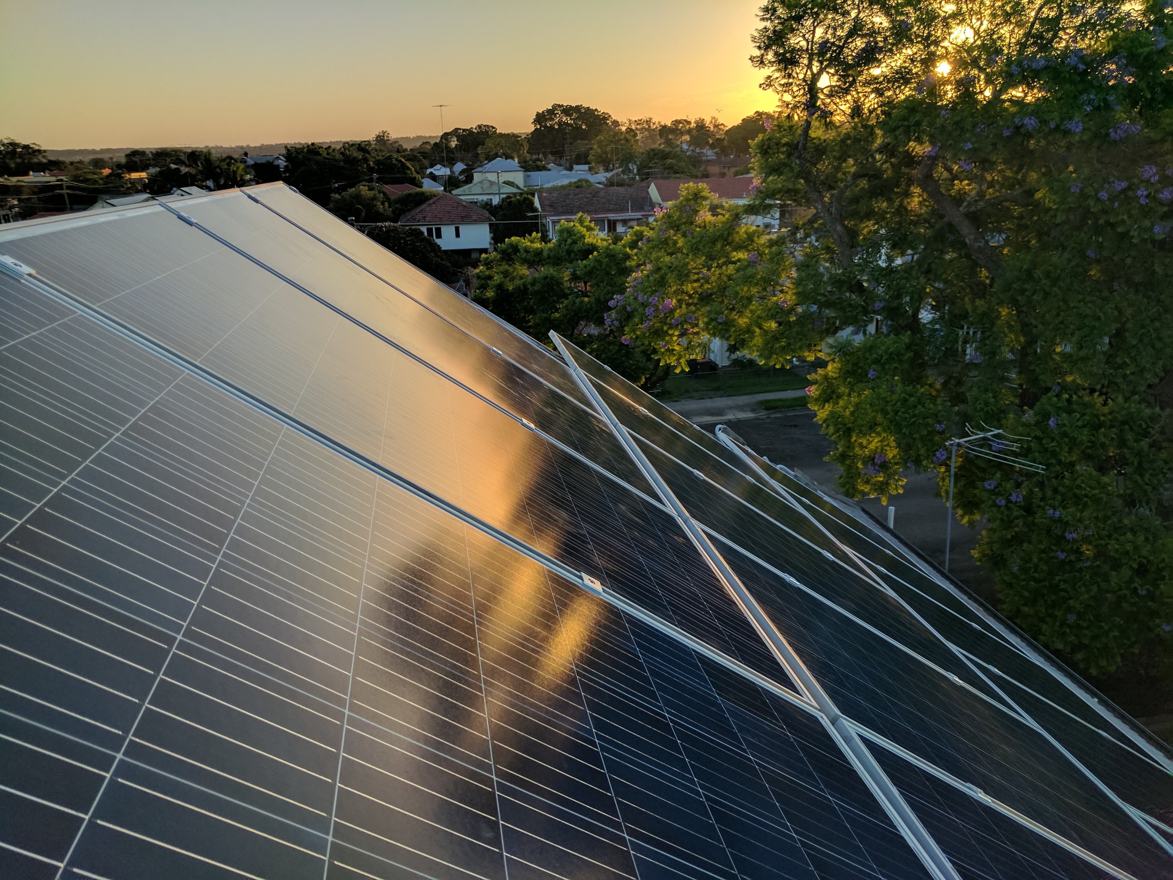 Wide view of a residential rooftop photovoltaic installation at low sun angle.