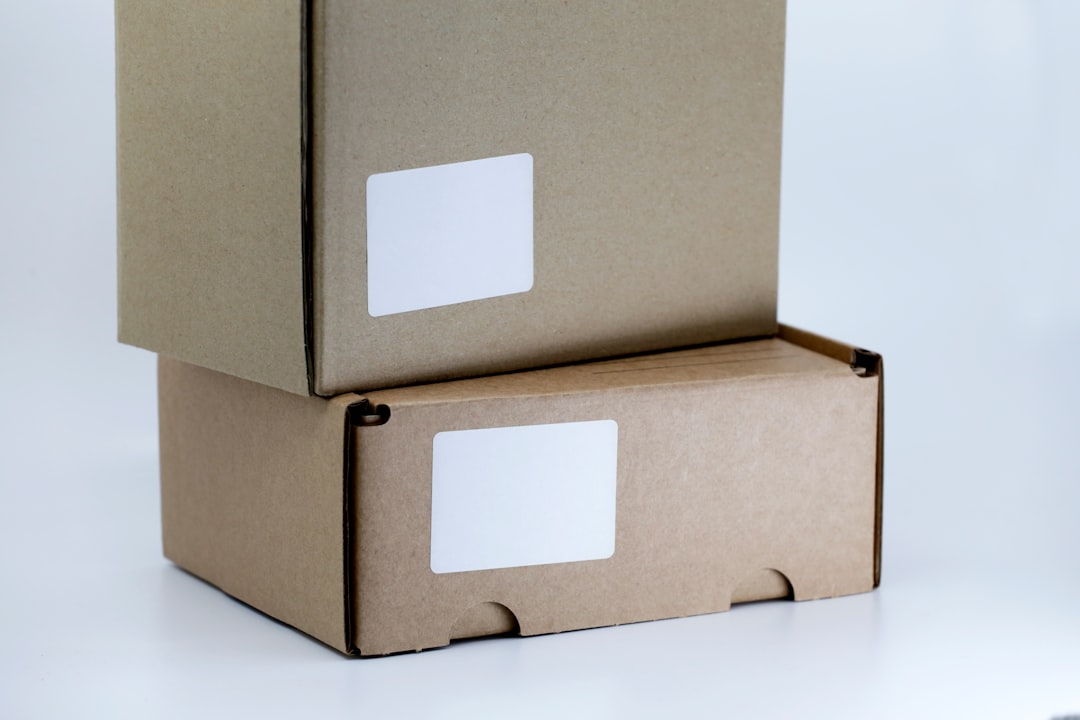 Two plain brown cardboard shipping boxes with blank white labels stacked on a white background.