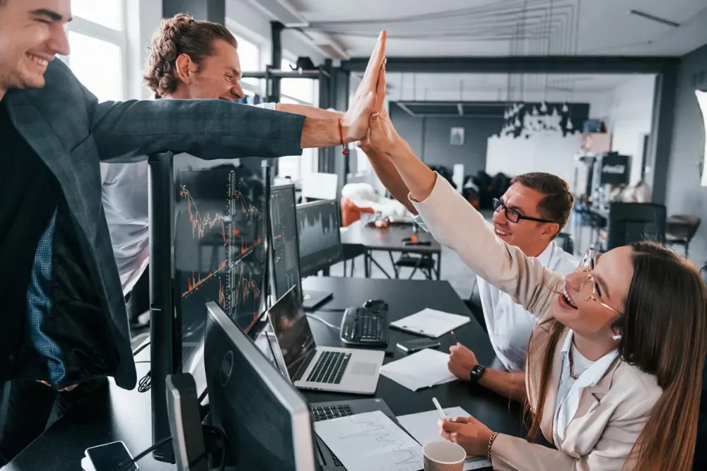 Colaboradores chocando las manos en la oficina, integración de equipos de trabajo con ASGAR