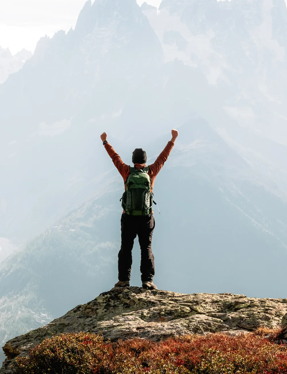 Persona celebrando en la cima de una montaña, símbolo del crecimiento que impulsa la capacitación