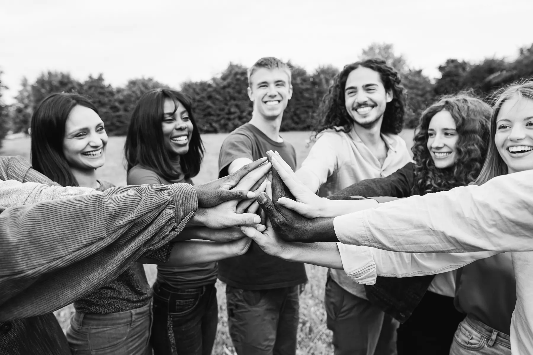Equipo de colaboradores uniendo las manos en una dinámica de team building al aire libre