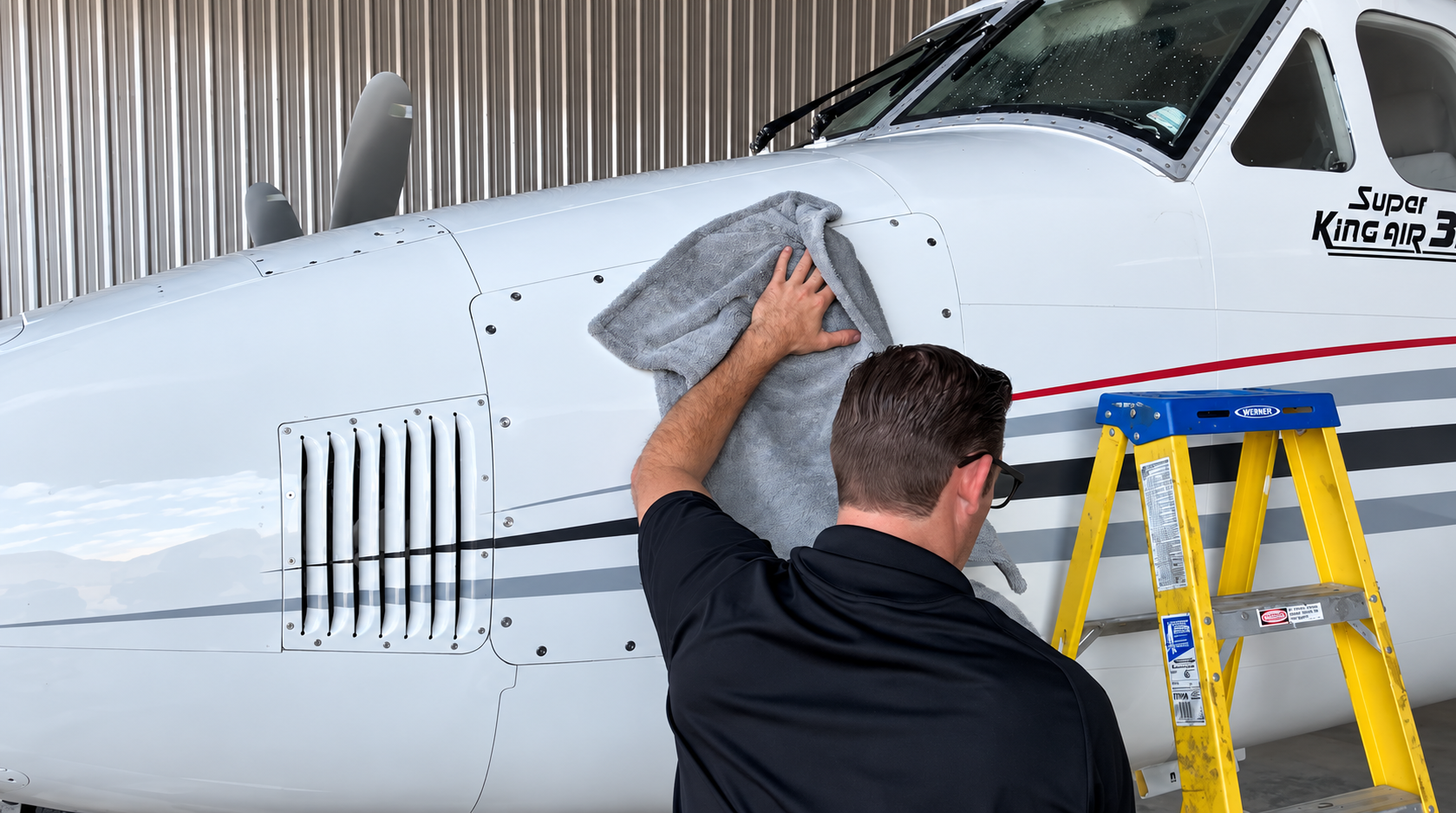 Detailer cleaning the exterior windows of a private jet cockpit