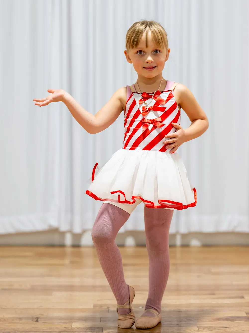 Young ballet student posing in a red and white costume at Ladu Dance Studio in Sandy, Utah