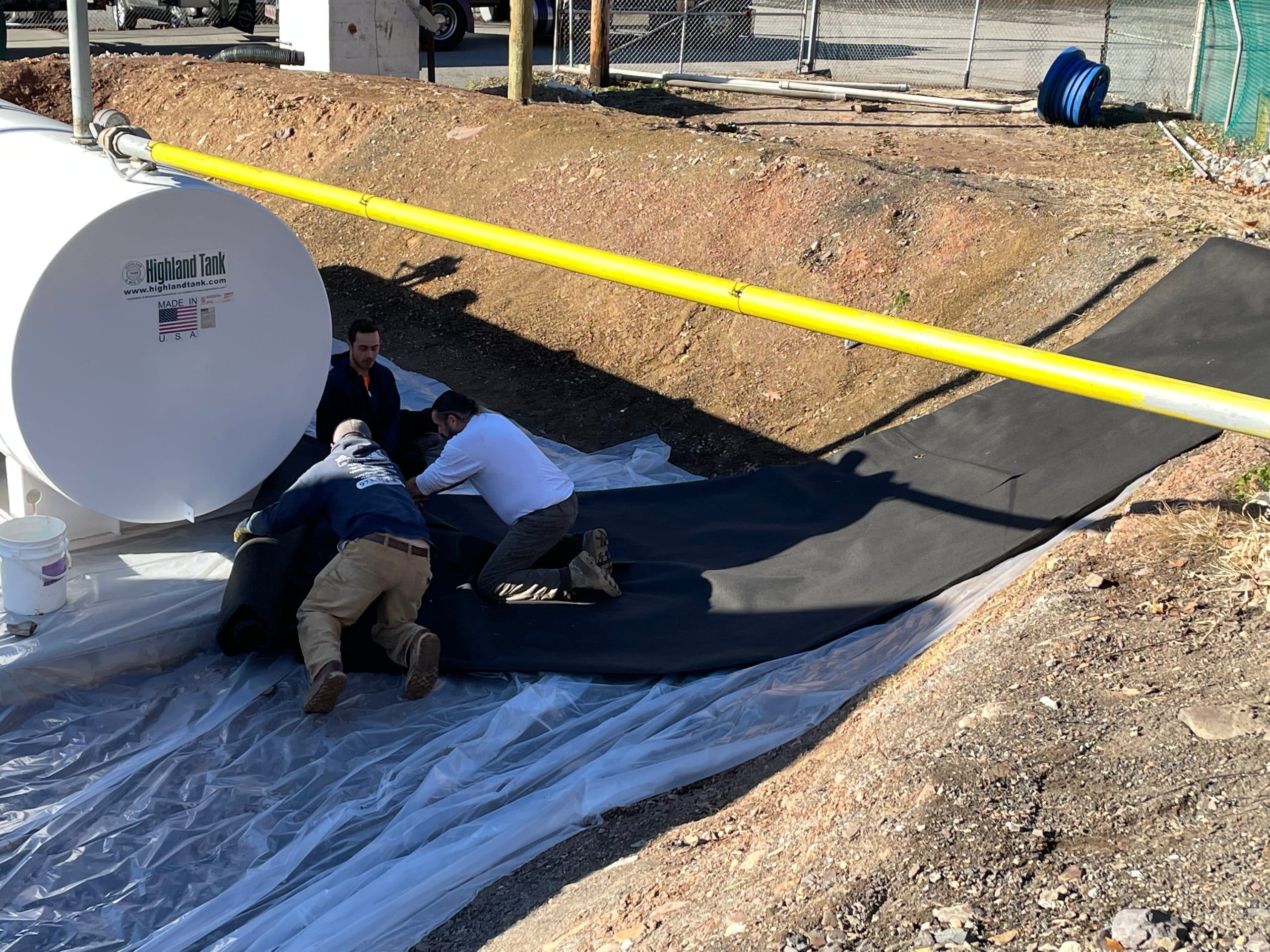 Crew rolling out underlayment fabric during containment installation