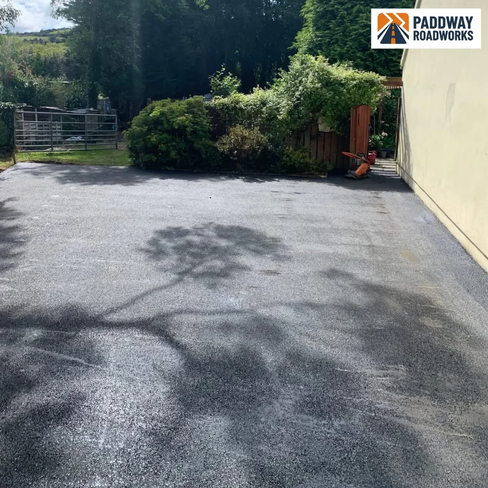 Tarmac driveway finished, dappled shadow from mature trees.