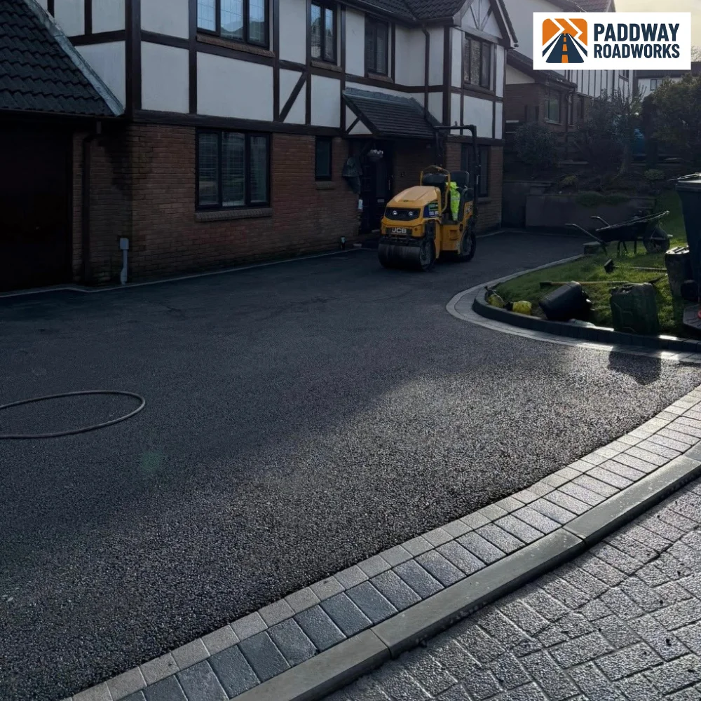 Tarmac driveway finished in front of detached house, 7.5-tonne tipper truck reversing in background.