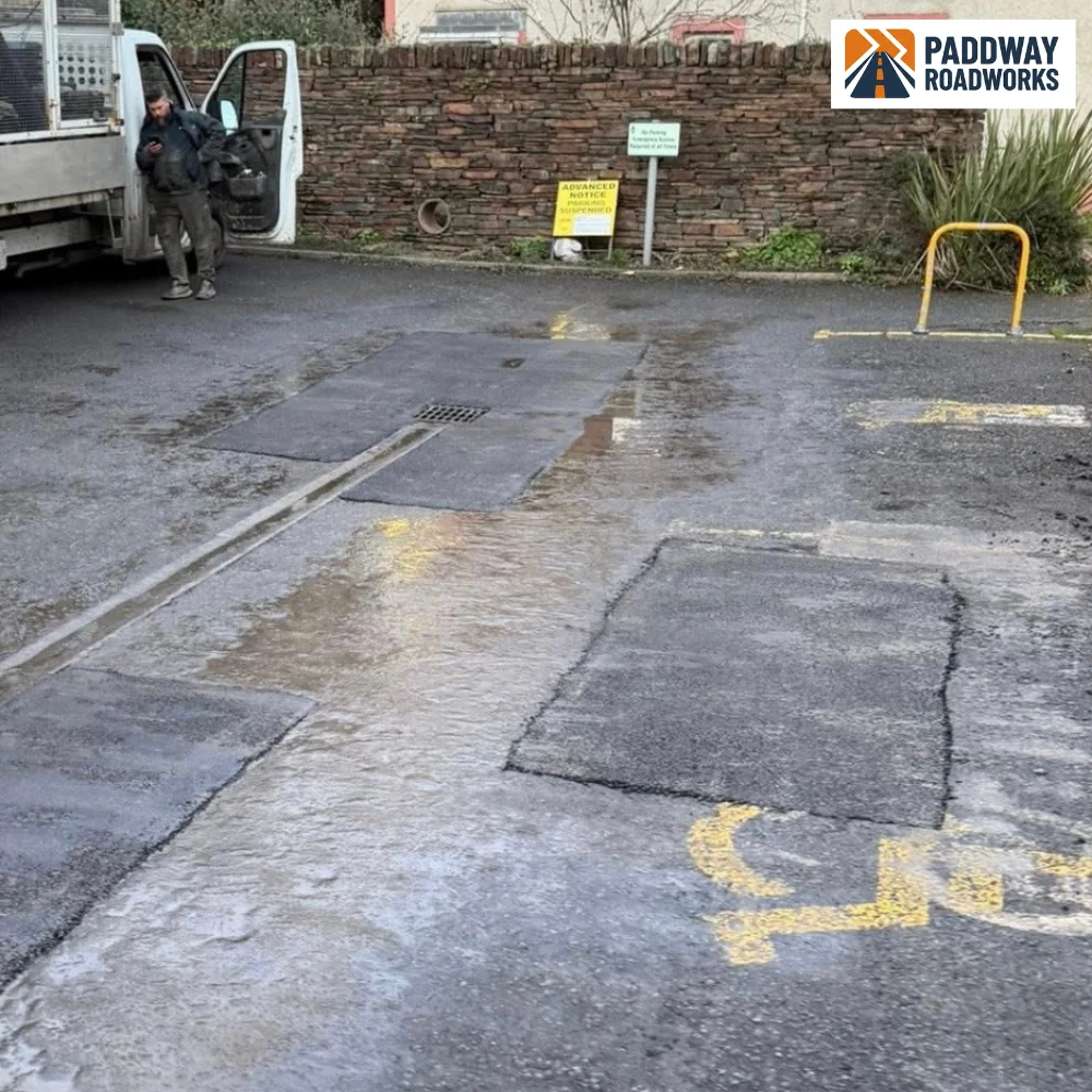 BEFORE — broken parking bay tarmac with white paint marking the area to repair.