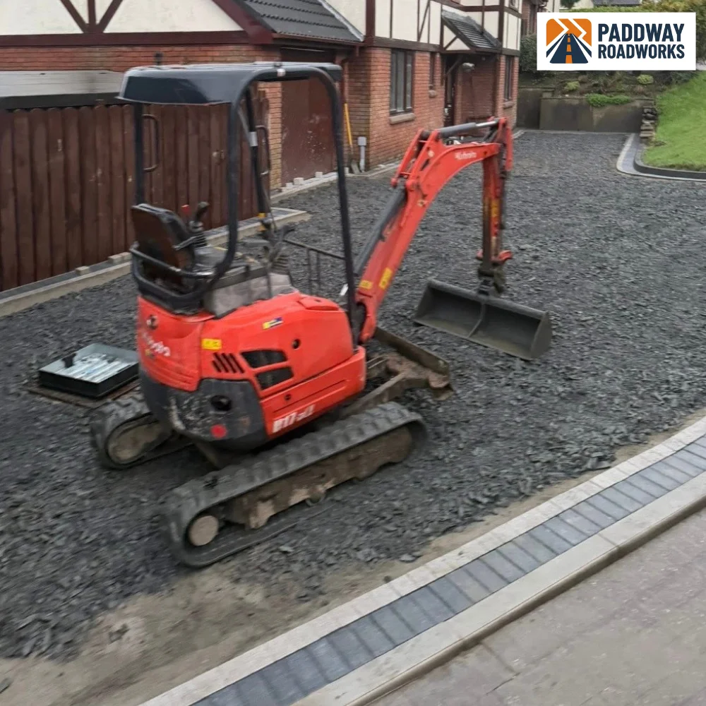 Kubota excavator on freshly poured concrete pad with red brick edge complete.