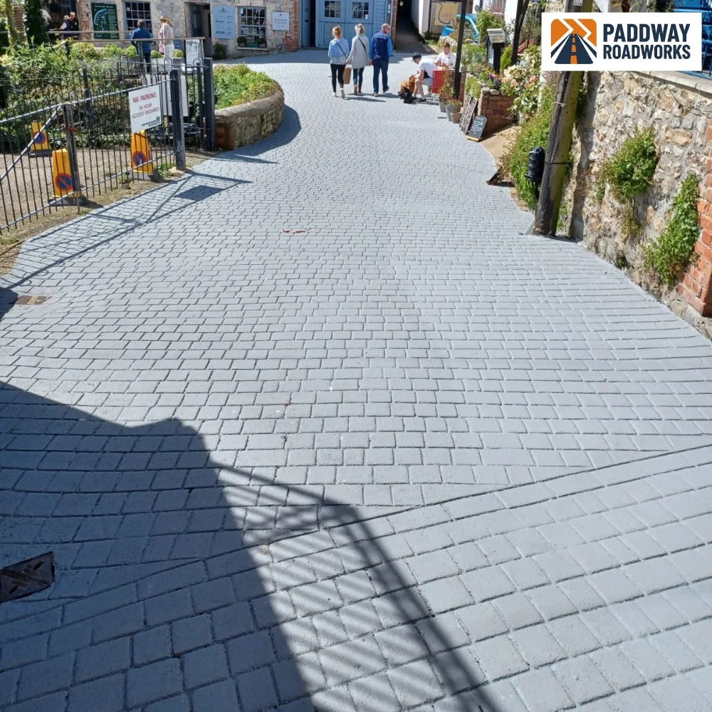 Block-paved public alleyway between properties — sunny day.