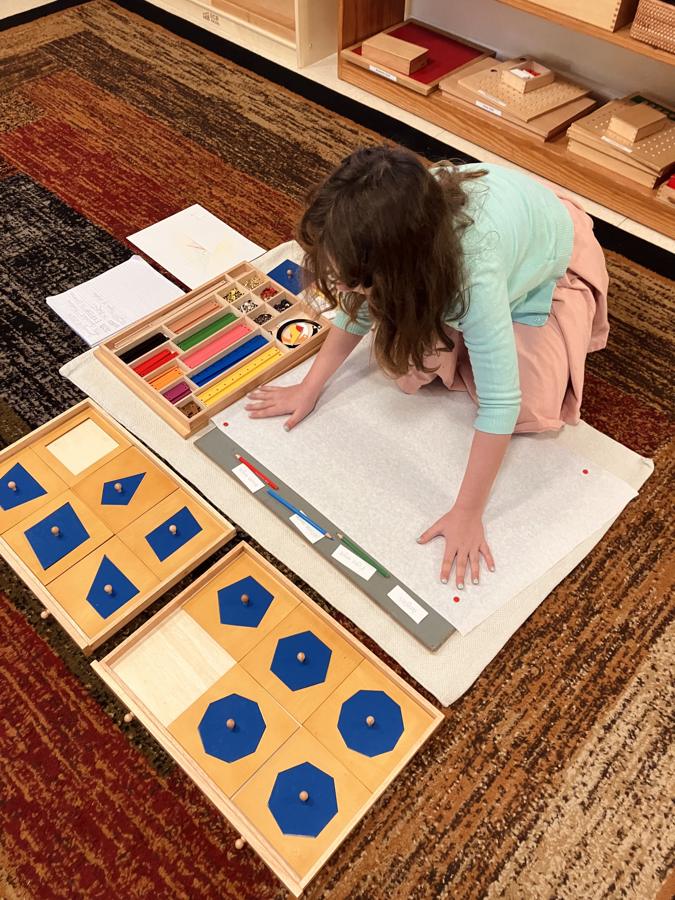A girl working with geometry materials on a floor mat