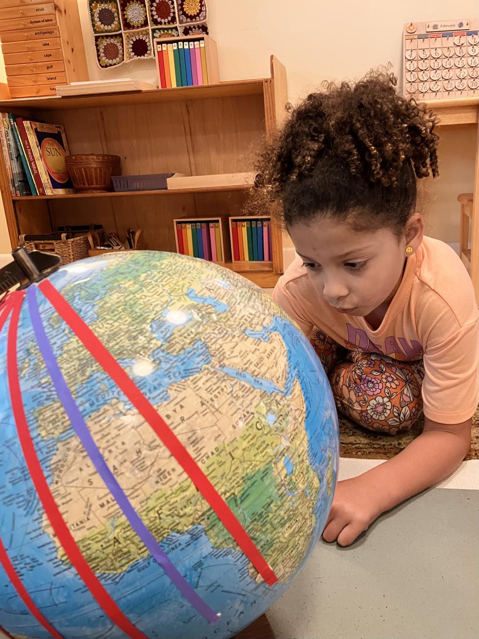 A young student studying a large classroom globe