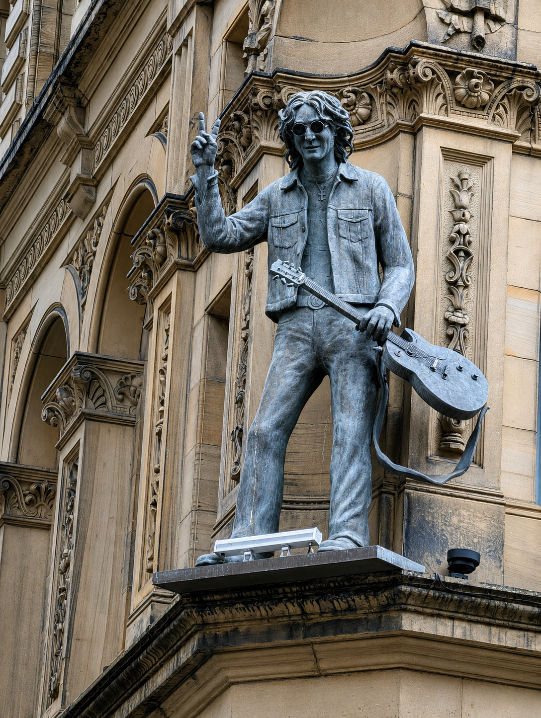 Close-up statue of a John Lennon with a guitar on a Liverpool building, reflecting creativity, legacy and the power of imagination.