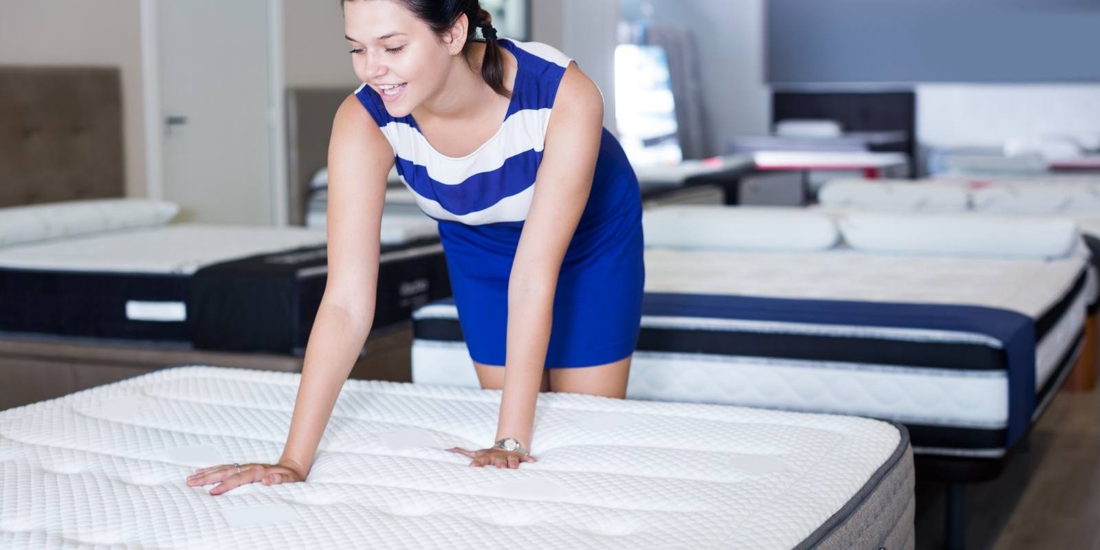 A woman checking mattresses at a mattress store A woman checking mattresses at a mattress store