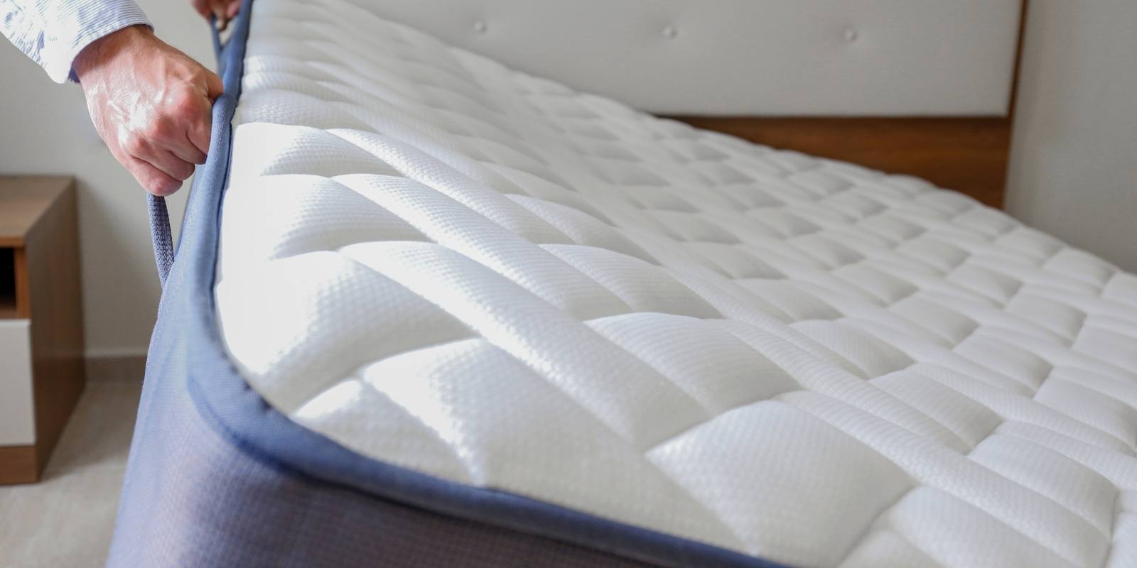 A new clean mattress being installed on a bed