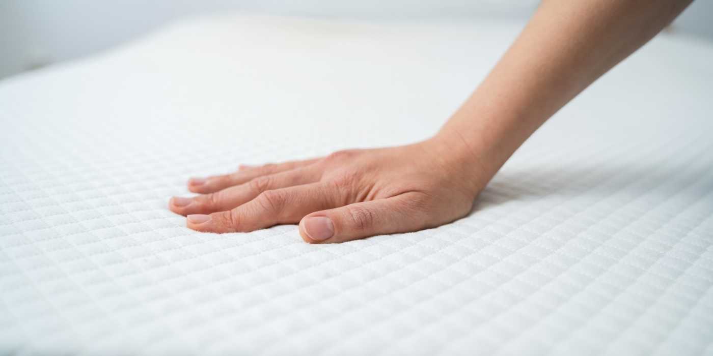 Hand touching a cool to the touch mattress surface showing the cooling fabric layer