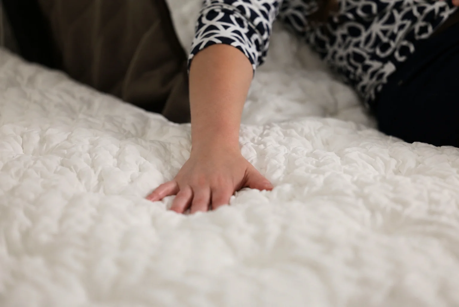 A hand pressing into the quilted top of a Bread Rest mattress
